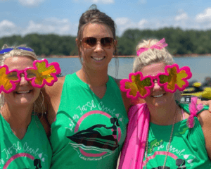 Three women wearing green Ladies Jet Ski Crawl shirts, smiling at camera with Lake Hartwell in the background.