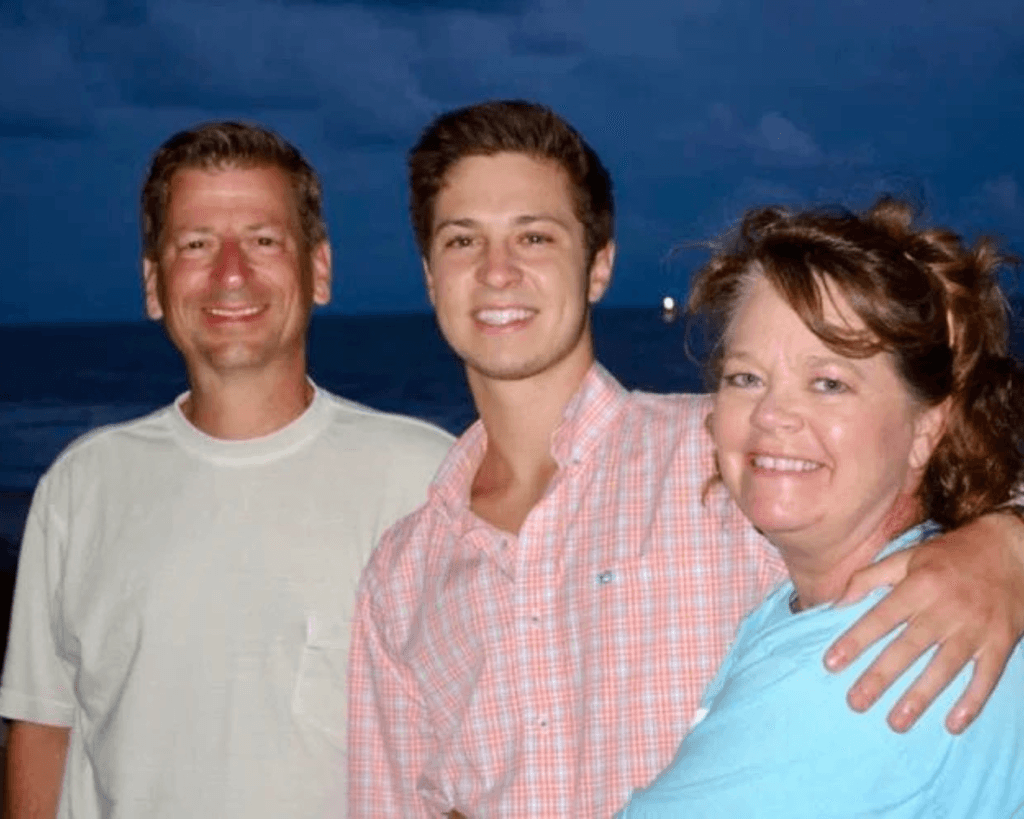 Tucker Hipps smiling with parents Cindy and Gary Hipps.